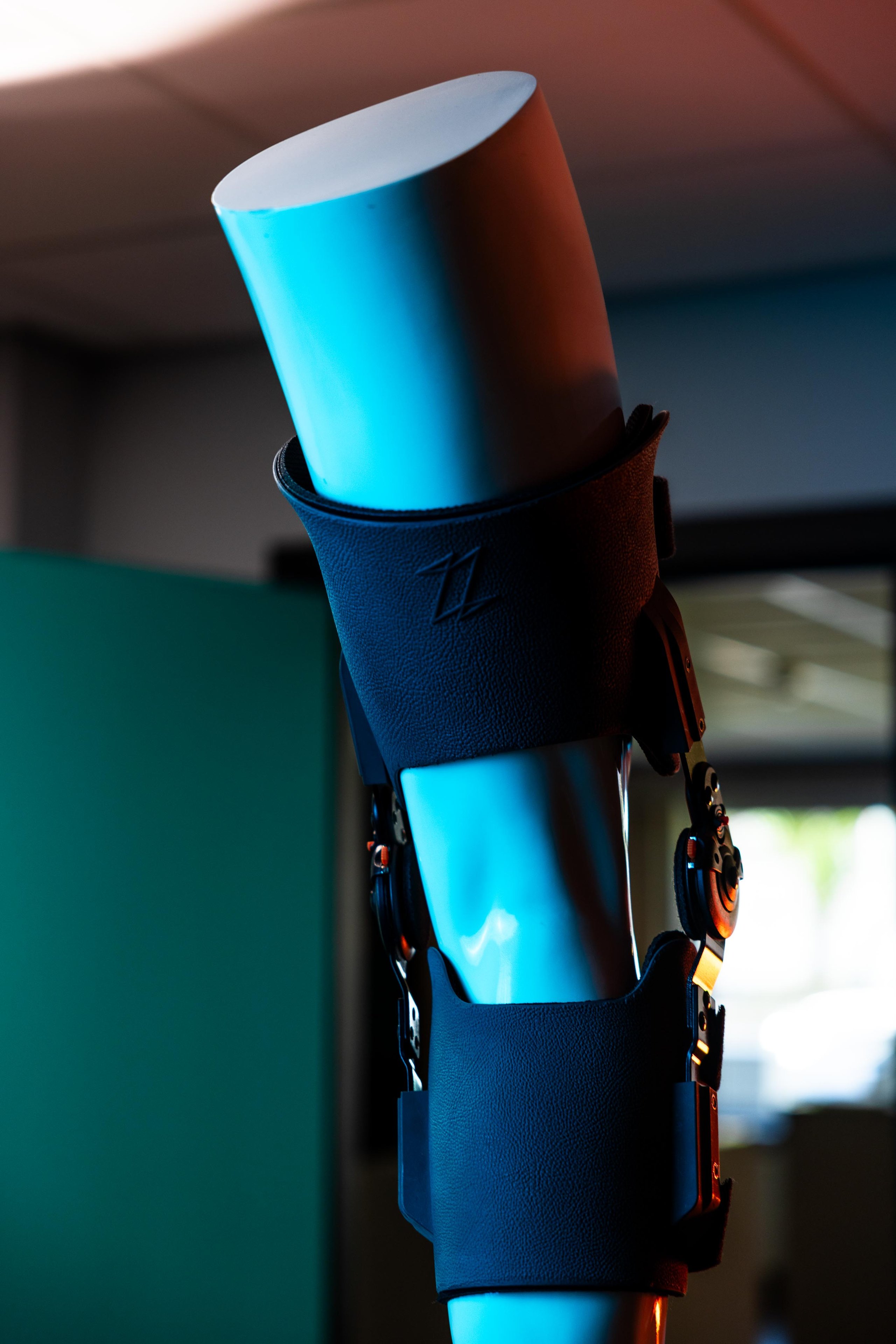 Bright blue cylindrical object secured in a dark blue fabric holder with metal attachment clips